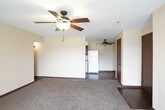 This single-floor unit offers a practical and functional layout across several well-defined living spaces. The living area is generously proportioned, featuring plush carpeting, neutral-toned walls, and a ceiling fan with a light fixture. A sliding glass door with vertical blinds fills the room with natural light and provides access to an outdoor area with views of surrounding greenery.

The layout includes multiple bedrooms, each finished with wall-to-wall carpeting, ceiling fans, and windows fitted with blinds. One bedroom features a spacious walk-in closet, while others offer convenient access via dark-toned interior doors that complement the warm color scheme throughout. Dark wood baseboards add a consistent design accent across the carpeted rooms.

The kitchen is designed for efficiency, offering ample dark cabinetry, laminate countertops, and hardwood-style flooring. White appliances—including a range, dishwasher, and over-the-range microwave—are neatly integrated into the galley-style layout.

The bathroom is well-appointed with a dark wood vanity, stone-look countertop, hardwood-style flooring, a full tub-shower combination, and coordinating dark hardware throughout. Textured ceilings are a consistent feature across all rooms.