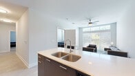 This well-appointed single-story residence offers a thoughtfully designed layout with 2 bedrooms, 3 bathrooms, and a bonus game room, making it a versatile and functional living space. Light wood-look flooring flows throughout, complementing the clean, modern aesthetic found in every room.

The open-concept kitchen and living area serves as the heart of the home. The kitchen features a large center island with a double-basin sink and light quartz countertop, dark cabinetry, stainless steel appliances including a refrigerator, range, microwave, and dishwasher, plus ample white upper cabinetry for storage. Bar-height seating at the island provides casual dining options.

The living room is bright and airy, benefiting from expansive windows that flood the space with natural light and offer outdoor views. A ceiling fan adds comfort, and the open layout connects seamlessly to the kitchen and dining area.

Both bedrooms are comfortably sized, each with access to closets, including walk-in closets with wire shelving systems. The primary bedroom offers a private feel with direct closet access. The three bathrooms are clean and functional, with at least one featuring a full soaking tub and shower combo with overhead cabinetry. In-unit laundry is also accessible from the bedroom corridor.