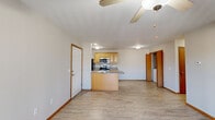Located at 1600 E Windmill Way in Republic, Missouri, this single-floor unit offers a practical and comfortable layout designed for everyday living. The open-concept living and kitchen area serves as the heart of the space, where light vinyl plank flooring extends throughout, lending a clean, cohesive aesthetic. A ceiling fan overhead provides both airflow and ambient lighting, while neutral-toned walls create a bright, welcoming atmosphere.

The kitchen is efficiently designed with warm honey-toned cabinetry offering generous storage, a peninsula with a built-in sink that doubles as a breakfast bar, and stainless steel appliances including a range, microwave, and dishwasher. A black refrigerator anchors the appliance suite. Adjacent to the kitchen, the living area flows naturally toward a sliding glass door that invites natural light.

The bedrooms feature plush carpet flooring and include well-organized closets with wire shelving systems. One bedroom benefits from a window with an outdoor view. A dedicated laundry closet houses a full-sized washer and dryer, adding notable convenience. The bathroom includes a full tub-shower combination with chrome fixtures. Warm wood-toned door trim and baseboards throughout provide a consistent, finished look across all rooms.