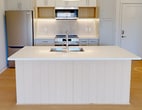 This 600 square foot, one-bedroom apartment in Fayetteville, AR, exemplifies modern urban living with its efficient design and contemporary aesthetics. The open-concept layout maximizes the use of space, creating a seamless flow between living areas. The kitchen is a standout feature, boasting sleek white cabinetry, stainless steel appliances, and a large central island with a built-in sink, perfect for meal preparation and casual dining. Light wood flooring throughout the main living areas adds warmth and continuity.

The bathroom is generously sized, featuring a combination tub-shower with a glass partition, a modern vanity with ample storage, and clean white tiles that enhance the sense of space. The bedroom, measuring 150 square feet, offers plush carpeting and large windows that provide natural light and urban views.

Throughout the apartment, recessed lighting and strategically placed windows ensure bright, airy spaces. The neutral color palette, predominantly whites and light tones, contributes to a fresh, contemporary ambiance. This thoughtfully designed apartment offers a perfect blend of style and functionality for modern city dwellers.