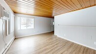 Located at 211 N Lincolnway St in North Aurora, Illinois, this single-floor, one-bedroom, one-bathroom home offers a compact yet functional layout with notable architectural character throughout. A defining feature of the space is the warm, natural wood-planked ceiling that runs consistently through multiple rooms, adding rustic charm and visual warmth against the crisp white walls.

The combined living and dining area provides an open, versatile space illuminated by multiple windows that invite natural light. Light-toned vinyl plank flooring extends across the living areas, complementing the wood ceiling above. Ceiling fans are present in several rooms, providing both airflow and a casual, comfortable ambiance.

The kitchen features stone-look tile flooring, gray cabinetry with dark countertops, a double sink, and stainless steel appliances including a gas range, dishwasher, and refrigerator. Baseboard heating runs throughout the home, ensuring warmth during colder months.

The bedroom includes its own ceiling fan, light plank flooring, and access to a spacious closet with a full hanging rod, shelving, and a window for natural light. The bathroom is clean and functional, with a window, gray vanity, and tile flooring consistent with the kitchen.

Additional highlights include three closets, a dedicated laundry area, a utility room, and a private entrance, making this home practical and well-organized.