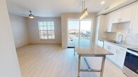 This contemporary 550 square foot apartment offers a thoughtfully designed living space in an urban setting. The open-concept layout maximizes the use of space, creating a seamless flow between the living areas. The kitchen is a standout feature, boasting crisp white cabinetry, stainless steel appliances, and a stylish pendant light fixture. A granite-topped island provides additional prep space and casual dining options.

The bathroom is elegantly appointed with large format tile, a glass-enclosed shower, and modern fixtures. The bedroom, measuring 130 square feet, offers ample space and is complemented by plush carpeting and a ceiling fan for comfort. Large windows throughout the apartment flood the space with natural light and offer impressive city views.

Light wood-look flooring in the main living areas adds warmth and continuity to the space. The apartment's neutral color palette creates a blank canvas for personalization. Additional features include recessed lighting, a full-sized washer and dryer, and ample closet space. This efficient one-bedroom unit combines style and functionality, perfect for urban living.