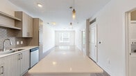 This well-appointed one-bedroom, one-bathroom apartment in Decatur, Georgia offers a thoughtfully designed layout that maximizes every square foot of its compact footprint. The open-concept kitchen and living area serves as the heart of the home, featuring wide-plank hardwood-style flooring, a generous island with a clean white quartz countertop, and elegant pendant lighting overhead. The kitchen is outfitted with a full suite of stainless steel appliances — including a refrigerator, range, microwave, and dishwasher — complemented by light wood cabinetry, a decorative tile backsplash in a honeycomb pattern, and ample counter space.

The living area extends the open floor plan, offering a bright and airy feel with light-toned walls and easy-care flooring. The bedroom is a comfortable retreat with plush wall-to-wall carpeting, large windows that invite generous natural light and views of surrounding greenery, and a ceiling fan for added comfort. A dedicated closet provides convenient storage.

The bathroom is clean and modern, finished with large-format tile flooring, a single vanity with understated cabinetry, and a glass-enclosed walk-in shower with subway tile surround. Throughout the unit, a neutral color palette and contemporary finishes create a cohesive, move-in-ready aesthetic.