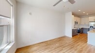 This well-designed one-bedroom, one-bathroom unit at 1803 S 46th St in Rogers, Arkansas, offers a clean, modern aesthetic with thoughtful finishes throughout. The open-concept living and kitchen area serves as the heart of the home, featuring light wood-look flooring, crisp white walls, and a ceiling fan overhead. The kitchen is a standout, boasting a large center island with a built-in sink, white quartz countertops, two-toned cabinetry with white upper and gray lower cabinets, a subway tile backsplash, and stainless steel appliances including a refrigerator, range, microwave, and dishwasher. Stylish pendant lights hang above the island, adding a contemporary touch. The living area opens to a private balcony through a glass door flanked by large windows fitted with roller shades, allowing ample natural light and outdoor views. The bedroom is carpeted and bright, with generous windows that bring in natural light. The bathroom features a double-sink vanity with gray cabinetry and quartz countertops, a large mirror with accent lighting, and a glass-enclosed subway tile shower. A dedicated closet with built-in wire shelving provides practical storage, completing this efficiently designed home.