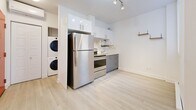 Located at 2238 Rue du Souvenir in Montréal, this efficiently designed one-bedroom, one-bathroom unit on the second floor makes clever use of its compact footprint. Light-toned hardwood-style flooring runs throughout, lending a cohesive and airy feel to the space.

The open-concept main area combines the living and kitchen zones seamlessly. The kitchen is well-appointed with two-tone cabinetry — white upper cabinets paired with grey lower units — stainless steel appliances including a full-size refrigerator and electric range, and a built-in hood vent. A stacked washer and dryer unit is neatly integrated into a dedicated alcove adjacent to the kitchen, offering in-unit laundry convenience. The living area features crisp white walls and a bright, clean aesthetic.

The bedroom is an intimate, cozy space with a window that admits natural light and includes a baseboard heater, ensuring year-round comfort.

The bathroom is finished with large-format white subway tiles surrounding a full soaking bathtub with a handheld shower fixture, a clean and functional design complemented by recessed lighting overhead.

Overall, the unit presents a bright, modern, and efficiently organized interior ideal for single occupancy.