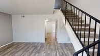 Located at 5350 Justin Dr NW in Albuquerque, New Mexico, this two-bedroom, two-bathroom two-story home offers a practical and well-organized layout spread across two floors. The main level features wood-look plank flooring throughout the living and kitchen areas, contributing to a clean, cohesive aesthetic. The kitchen is equipped with white cabinetry, light stone-patterned countertops, a stainless steel sink, a gas range, and a dishwasher — providing a fully functional cooking space. A hallway on the main level connects key areas and leads to a bright, windowed corridor. A standout architectural feature is the staircase adorned with decorative wrought iron railings, adding a touch of character to the interior. Both bathrooms are finished in a clean, bright style with white vanities, mirrored medicine cabinets, and wood-look flooring. The upper level houses the bedrooms, each carpeted for comfort. Both bedrooms feature sliding-door closets, wall sconce lighting, and windows that bring in natural light. The primary bedroom offers a generous closet with full-width sliding mirror doors. Textured ceilings are present throughout, and the home includes multiple closets for additional storage.