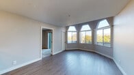 This two-bedroom, two-bathroom unit at Fieldstone is laid out on a single floor, offering a well-organized and functional living environment. The living area is a standout space, distinguished by a bank of large, architecturally angled clerestory windows that flood the room with natural light and frame views of surrounding greenery. Durable hardwood-style flooring runs throughout the main living area, lending a clean, modern aesthetic.

The kitchen features a peninsula with a dark countertop that provides both prep space and a casual dining surface. White shaker-style cabinetry offers ample storage, while stainless steel appliances—including a range, oven, and dishwasher—complete the space. Pendant lighting adds a refined touch overhead.

Both bedrooms are carpeted for comfort and are generously proportioned. Each bedroom includes direct outdoor access through a sliding glass door that opens to a private balcony with tree-lined views. Sliding mirrored closet doors provide practical storage solutions.

The two bathrooms each feature wood-style flooring, white cabinetry with dark countertops, and a tub-shower combination. The neutral color palette throughout the unit creates a cohesive and inviting atmosphere.