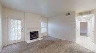 This single-story residence offers a thoughtfully arranged floor plan with a bright, open living area as its centerpiece. The living room is finished with plush carpet and features a classic wood-framed fireplace set against crisp white walls, creating a welcoming focal point. A window positioned above the fireplace mantel allows natural light to filter in, enhancing the room's airy feel. The entry foyer transitions seamlessly from tile to carpet, providing a practical and defined entry point.

The kitchen is equipped with warm oak cabinetry extending to the upper walls, offering generous storage. White appliances, including a refrigerator, electric range, over-the-range microwave, and dishwasher, are paired with light countertops and easy-to-maintain tile flooring.

The bedrooms are carpeted and well-proportioned, each featuring a ceiling fan with light fixture and windows that bring in natural light and outdoor views. The primary bathroom includes a dual-sink vanity with oak cabinetry, a large mirror with overhead lighting, and a tub-shower combination over tile flooring. A second full bathroom mirrors this layout with a single-sink vanity and tub-shower combo, also finished in tile.