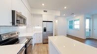 Located at 489 N McDowell Blvd in Petaluma, CA, this thoughtfully designed one-bedroom, one-bathroom residence offers a clean, modern aesthetic across a well-proportioned single-floor layout. Light-toned, wood-look flooring runs throughout the space, providing a warm and cohesive foundation that complements the crisp white walls and recessed lighting found in every room.

The kitchen is a standout feature, showcasing floor-to-ceiling white shaker cabinetry, a white subway tile backsplash, and a full suite of stainless steel appliances including a range, microwave, and French door refrigerator. A central island with a bright white countertop adds valuable workspace and a casual dining option, while the open layout connects naturally to the living area.

The living room benefits from multiple windows that bring in generous natural light, with access to a private balcony for outdoor enjoyment. The bedroom is a comfortable, well-lit retreat with a ceiling fan, natural light from a window with blinds, and direct access to a spacious walk-in closet outfitted with multi-level shelving and hanging rods.

The bathroom features white cabinetry, a single vanity with a framed mirror, built-in open shelving for storage, and consistent wood-look flooring. Clean lines and a neutral palette give the entire residence a fresh, move-in-ready feel.