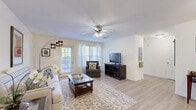 Located in Clarksville, Tennessee, this two-bedroom, two-bathroom single-floor residence offers a practical and comfortable layout across a well-utilized footprint. The living room serves as the central gathering space, featuring light wood-style flooring, a ceiling fan, and large windows with sheer curtains that allow generous natural light to fill the room. A sliding glass door provides direct access to a private patio, extending the living area outdoors. The kitchen is efficiently designed with light wood cabinetry, white appliances including a range, dishwasher, and refrigerator, ample counter space, and a pass-through view into the adjacent laundry area. The dedicated laundry space includes an in-unit washer and overhead shelving for added storage convenience. The primary bedroom is a well-proportioned retreat featuring large windows that bring in natural light, light wood flooring, and double closets offering substantial storage. Both bathrooms feature light wood cabinetry vanities, large mirrors, and shower/tub combinations with clean, neutral finishes. Throughout the residence, the consistent light wood flooring, neutral wall tones, and bright lighting create a cohesive and welcoming ambiance. A hallway connects the bedrooms and bathrooms, rounding out this functional single-level home.