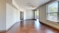 This well-appointed three-bedroom, two-bathroom unit is thoughtfully laid out across a single primary floor, making efficient use of its space. The open-concept kitchen serves as a central hub, outfitted with warm-toned wood cabinetry, black appliances including a range, microwave, and dishwasher, a stainless steel refrigerator, and a generous granite-style island with built-in shelving. Track lighting illuminates the kitchen, which flows seamlessly into the living area, where hardwood-style flooring, a ceiling fan, and large windows invite abundant natural light. A sliding glass door in the living room provides direct balcony access with outdoor views.

The primary bedroom is a well-sized retreat featuring hardwood-style flooring, a ceiling fan, a sliding glass door to a private balcony, and an adjacent closet. The additional bedrooms are finished with plush carpet, ceiling fans, and windows with outdoor views. Two full bathrooms mirror each other in design, each featuring rich wood vanities with granite-style countertops, large mirrors, hardwood-style flooring, and a full tub-shower combination. Two closets provide practical storage throughout the unit.