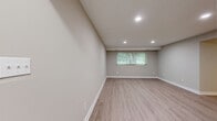 This well-appointed 2-bedroom, 2-bathroom single-floor residence at 736 Camberley Cir in Towson, Maryland offers a clean, modern aesthetic throughout. Light wood-style luxury flooring flows through the main living areas, complemented by neutral warm-gray walls and crisp white baseboards that create a bright, cohesive look. The open living and dining area is spacious and airy, featuring a ceiling fan with light fixture and recessed lighting, with easy access to the entry hallway.

The kitchen is thoughtfully designed with abundant white shaker-style cabinetry, matte black hardware, white countertops, and stainless steel appliances including a dishwasher. A window above the sink brings in natural light, enhancing the clean, functional workspace.

Both bedrooms are well-sized and finished with plush wall-to-wall carpeting and ceiling fans. The generously proportioned primary bedroom includes multiple closets with built-in shelving and hanging rods, offering exceptional storage. A large window provides natural light and views of the surrounding greenery. The second bedroom also features a window and ceiling fan.

The bathrooms include a tiled bath with a glass-enclosed shower stall, white tile wainscoting, and a window for ventilation. A utility room and seven closets throughout the home ensure ample storage for everyday living.