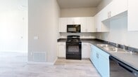This well-designed single-floor residence in Greeley, Colorado offers three bedrooms and two full bathrooms within a thoughtfully laid-out floor plan. The kitchen is outfitted with crisp white cabinetry, dark countertops, a full suite of black appliances including a refrigerator, range, microwave, and dishwasher, and a double-basin sink — all set on light wood-look flooring that extends throughout the main living areas. A bright hallway connects the kitchen to the rest of the home, providing a clean and open flow between spaces. The bedrooms are comfortably sized, with the primary bedroom featuring light wood-look flooring, a ceiling fan, and a window that allows natural light to fill the room. Additional bedrooms are carpeted and receive generous natural light through large windows with blinds. One bedroom offers convenient access to the in-unit washer, adding everyday practicality. Both bathrooms include full tub-shower combos with built-in shelving and clean white surrounds. A dedicated closet provides additional storage. Throughout the home, neutral tones, white trim, and consistent finishes create a cohesive, move-in-ready aesthetic that is both functional and inviting.