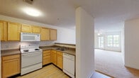 Located at 2792 Stantonsburg Rd in Greenville, NC, this single-floor unit offers a practical and comfortable layout designed for everyday living. The kitchen is outfitted with light wood cabinetry, a double-basin sink, a white electric range, a built-in microwave, and a dishwasher, all set on easy-care hardwood-style flooring. A half-wall peninsula separates the kitchen from the adjoining living area, creating an open, connected feel while maintaining a distinct sense of each space. The living area is generously sized, featuring soft wall-to-wall carpeting, a ceiling fan with light fixture, and a set of French doors that flood the room with natural light and provide access to the outdoors. Additional bedrooms are carpeted and well-lit, each benefiting from windows that bring in natural light, ceiling fans, and ample closet space including a paneled double-door closet in one room. The bathrooms feature hardwood-style flooring, a tub-shower combination, toilet, and a vanity with warm wood cabinetry and a large mirror. Throughout the unit, textured ceilings, neutral wall tones, and clean finishes contribute to a bright and move-in-ready atmosphere.