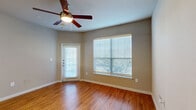 Located at 1900 Westview Blvd in Conroe, TX, this single-floor, one-bedroom, one-bathroom unit offers a practical and comfortable layout. The living room is bright and welcoming, featuring warm hardwood-style flooring, a ceiling fan with light fixture, and large windows fitted with horizontal blinds that allow generous natural light. A private exterior door leads directly from the living area, adding convenience and accessibility. The galley-style kitchen is efficiently designed with warm wood cabinetry, granite-look countertops, a built-in sink, and black appliances including a refrigerator, stove, and microwave. An arched pass-through opening connects the kitchen to the living space, enhancing the open feel. The bedroom is carpeted for comfort, features its own ceiling fan, and includes a window overlooking greenery outside. A dedicated closet provides storage. The full bathroom is well-appointed with a single vanity topped with granite-look counters, wood cabinetry below, a tiled tub-shower combination, and neutral tile flooring. Throughout the unit, neutral taupe-toned walls create a cohesive and versatile aesthetic, offering a clean canvas for personalization.