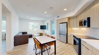 Located at 555 Research Park Dr. in Davis, CA, this well-designed one-bedroom, one-bathroom unit offers a clean, modern aesthetic across a single floor. Light wood-tone vinyl flooring runs throughout, creating a cohesive and bright atmosphere. The open-concept layout seamlessly connects the kitchen, dining, and living areas, maximizing the functional use of space. The kitchen is appointed with light wood cabinetry, white quartz countertops, stainless steel appliances including a full-size refrigerator, electric range, microwave, and dishwasher, along with a large window that brings in natural light. A dining area with a four-seat table sits adjacent to the kitchen, flowing into the living room, which features a window with outdoor views and recessed lighting overhead. The bedroom is a well-proportioned private retreat with a ceiling fan, a window overlooking the outdoors, and a closet. The bathroom is finished in a clean, minimalist style with light wood floating vanity, brushed gold fixtures, a large mirror, and a tiled shower-tub combo. In-unit laundry and additional closet storage round out this efficiently laid-out residence.