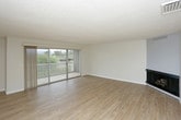 This single-floor residence offers a clean, functional layout with light hardwood-style flooring running throughout the main living areas and bedrooms, creating a cohesive and easy-to-maintain interior. The open living room is a standout space, featuring large sliding glass doors that lead to a balcony with outdoor views, allowing abundant natural light to fill the room. A ceiling fan provides additional comfort, while a textured ceiling adds subtle architectural character.

The kitchen is well-equipped with granite-style countertops, warm wood cabinetry, a stainless steel sink with a modern pull-down faucet, and a dishwasher. A window above the sink overlooks greenery, making the space feel bright and connected to the outdoors.

The bedrooms are comfortably sized, each featuring hardwood-style flooring, textured ceilings, and windows that invite natural light. One bedroom includes mirrored sliding closet doors, maximizing both storage and the sense of space. A vanity area with warm wood cabinetry and a lighted mirror is also present within the layout.

The bathroom is neatly finished with tile flooring, a wood-toned vanity, a wide mirror with overhead lighting, and a tub-shower combination enclosed by sliding glass doors. Throughout, neutral tones and clean lines create a calm, move-in-ready atmosphere.