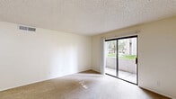 Located at 1249 E Spence Ave in Tempe, Arizona, this 2-bedroom, 2-bathroom residence offers a practical and comfortable single-floor layout. The spacious living room is finished with plush carpeting and a textured ceiling, and features large sliding glass doors that open onto a private balcony, allowing natural light to fill the room while offering views of the surrounding greenery. The kitchen and dining area are combined into one functional space, showcasing warm wood-tone cabinetry, a peninsula counter with a breakfast bar, a double-basin sink, and a full suite of white appliances including a refrigerator and electric range. Wood-style flooring runs throughout the kitchen and dining area, contrasting with the soft carpeting found elsewhere. A dedicated pantry provides additional storage. Both bedrooms are carpeted and feature ceiling fans and angled corner windows fitted with vertical blinds, letting in ample natural light. Three closets throughout the unit offer generous storage. The primary bedroom includes its own en-suite bathroom, while the second full bathroom serves the remaining areas of the home. Each bathroom is equipped with a tub/shower combination and wood-toned vanity cabinetry. A connecting hallway ties all rooms together in a cohesive and efficient floor plan.