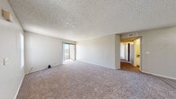 Located at 3800 S Nellis Blvd in Las Vegas, NV, this 2-bedroom, 2-bathroom unit offers a practical and comfortable single-floor layout. The spacious living room is carpeted and bathed in natural light, with a sliding glass door opening to a private balcony that provides outdoor views. The open layout connects the living room to the dining area for easy flow between spaces. The kitchen features white cabinetry, dark countertops, wood-look flooring, and a full-size refrigerator, providing ample storage and workspace. Both bedrooms are carpeted with neutral tones and feature windows with vertical blinds that allow natural light. The primary bedroom is generously sized and includes closet space. The bathrooms are finished with white vanity cabinetry, dark countertops, and wood-look flooring, with one bath offering a shower-tub combination. A dedicated in-unit laundry room houses a full-size washer and dryer with additional shelving for storage. Three closets throughout the unit offer excellent organizational capacity. Textured ceilings are consistent throughout, adding a classic residential character to the overall ambiance.