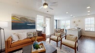 This single-floor residence is designed with a clean, contemporary aesthetic, combining functionality with modern finishes. The open-concept living area is anchored by wood-look flooring, a ceiling fan with integrated lighting, and generous natural light streaming through multiple windows fitted with plantation-style blinds. The living space flows seamlessly into a dedicated dining area, which benefits from a wall of windows offering outdoor views, creating a bright and airy atmosphere throughout.

The kitchen is well-equipped, featuring gray shaker-style cabinetry, granite-look countertops, stainless steel appliances, and a central island with a built-in sink — an efficient and stylish workspace that connects directly to the living and dining zones.

A carpeted primary bedroom features a bold teal accent wall, ceiling-height details, and direct access to a private en-suite area. A second bedroom offers plush carpet, a ceiling fan, natural light, and ample space. The bathroom includes a granite-topped vanity with gray cabinetry, wood-look flooring, and a shower-tub combination. A clean hallway with panel doors connects the private rooms, maintaining an organized and cohesive layout throughout.