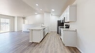 Located at 960 County Road B in Shawano, Wisconsin, this thoughtfully designed 2-bedroom, 2-bathroom residence offers a clean, modern aesthetic throughout its single-floor layout. The open-concept living area combines the living room, dining room, and kitchen into one cohesive space, with sliding glass doors that lead to a private balcony and invite natural light inside. The kitchen is a standout feature, showcasing white shaker-style cabinetry, stone-look countertops with a large island, a stainless steel undermount sink, and a full suite of stainless steel appliances including a refrigerator, range, microwave, and dishwasher. Recessed lighting illuminates the space with a bright, polished feel. Both bedrooms are carpeted and include ceiling fans, with the primary bedroom offering a generous footprint and access to a dedicated closet. The two bathrooms are finished with wood-look luxury vinyl plank flooring, white cabinetry, granite-style countertops, and brushed nickel hardware — one featuring a tub/shower combo and the other a walk-in shower. Additional conveniences include an in-unit laundry area and two closets. The neutral color palette and consistent finishes throughout create a cohesive, move-in-ready environment.