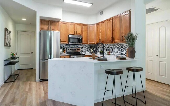 Cocina elegante con electrodomésticos de acero inoxidable y salpicadero de azulejos llamativos - Desert Parks Vista