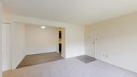 This single-floor residence offers a practical and comfortable layout designed to maximize everyday livability. The open living area is finished with plush carpeting and neutral cream-toned walls, creating a bright and welcoming atmosphere. A large sliding glass door floods the space with natural light and provides direct access to an outdoor green area, while vertical blinds offer privacy and light control. The living space connects seamlessly to an adjacent area with wood-look flooring, adding visual variety to the floor plan.

The galley-style kitchen is thoughtfully designed with dark espresso cabinetry, sleek white quartz countertops, and wood-look vinyl plank flooring. It is equipped with stainless steel appliances including a gas range, built-in microwave, and black refrigerator, along with a single-basin sink — offering a well-organized and functional cooking space.

The bedroom features soft carpeting and a bright window with exterior views, contributing to a calm and restful environment. The residence includes two bathrooms: one with a glass-enclosed walk-in shower and wood-look flooring, and a second with a full tub-shower combination and tiled surround. Both bathrooms are finished with white vanities and vinyl plank flooring. A dedicated laundry area houses a full-size top-loading washer and dryer, adding an essential convenience to this well-rounded home.