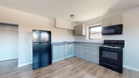 Located at 2201 Vails Gate Heights Dr in New Windsor, NY, this two-bedroom, one-bathroom single-floor home offers a thoughtfully laid-out living space with modern finishes throughout. The kitchen is a standout feature, showcasing an L-shaped layout with soft gray-blue shaker-style cabinetry, gray countertops, and black appliances including a refrigerator, electric range, and over-the-range microwave. A window above the sink brings in natural light, complementing the light wood-look flooring that extends throughout the home. The generously sized primary bedroom offers ample room, featuring a ceiling fan, a window with outdoor views, and baseboard heating. The second bedroom is a comfortable size and includes a sliding-door closet, neutral gray walls, and the same warm flooring. The bathroom is clean and bright, outfitted with white tile, a full tub-shower combo, a white vanity with sink, and a window that allows natural light to filter in. A connecting hallway links all rooms efficiently. Neutral gray tones on the walls throughout the home create a cohesive, modern aesthetic that is both practical and inviting.