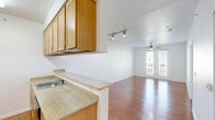 Located at 3801 Berkman Dr in Austin, TX, this one-bedroom, one-bathroom residence offers a well-organized single-floor layout with consistent wood-style flooring throughout. The open-concept kitchen and living area form the heart of the home, with the kitchen featuring light wood cabinetry, granite-style countertops, a stainless steel refrigerator, range, and built-in microwave, plus a peninsula with a sink that opens toward the living space. The living room is bright and airy, illuminated by track lighting and a ceiling fan, and anchored by a set of French doors that invite natural light and provide outdoor access. The bedroom is a comfortable, well-proportioned space equipped with its own ceiling fan and a large window overlooking the outdoors, ensuring ample natural light. Two closets serve the unit, including a walk-in closet outfitted with multiple hanging rods and shelving for generous storage. The full bathroom features a tub/shower combination with white tile surround, a vanity with cabinetry, and wood-style flooring that ties in with the rest of the home. Clean white walls and consistent finishes throughout lend the space a cohesive, move-in-ready aesthetic.