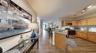 Located on Franklin Street in Hampton, Virginia, this single-floor residence offers a thoughtfully designed open-concept layout that seamlessly connects the main living areas. Wood-look plank flooring flows through the entryway, kitchen, dining, and living areas, lending a warm and cohesive aesthetic throughout.

The kitchen is outfitted with warm honey-toned cabinetry, granite countertops, a subway tile backsplash, and stainless steel appliances, including a range and over-the-range microwave. A peninsula with bar seating bridges the kitchen to the main living space, making it ideal for both casual meals and entertaining.

The living room is bright and welcoming, featuring crown molding, wood-look flooring, and direct access to an outdoor balcony through large glass doors that invite natural light. A dedicated dining area provides an intimate setting just off the main living space.

The primary bedroom is generously sized with plush carpet, multiple windows offering outdoor views, and ample natural light. A secondary bedroom also features carpet, large windows, and space for a desk, making it versatile as a guest room or home office. The bathroom includes a granite-topped vanity with warm wood cabinetry and wood-look flooring. The space combines functional design with comfortable, modern finishes throughout.