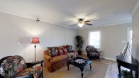 This two-story residence offers two bedrooms and one and a half bathrooms across a well-utilized floor plan designed for comfortable everyday living. The upgraded unit features classic architectural details, including crown molding that frames the living room walls and ceiling, adding a refined touch to the space.

The living room serves as the heart of the home, offering a welcoming and cozy atmosphere. A ceiling fan with a built-in light fixture is centrally positioned, providing both air circulation and ambient lighting. A window along one wall allows natural light to filter into the room, brightening the neutral-toned walls and carpeted flooring. Track lighting is also present, offering supplemental illumination. The room provides ample space for seating arrangements and casual furniture groupings.

The half bathroom on the main level adds everyday convenience, while the full bathroom is located upstairs alongside the two bedrooms. The two-story layout provides a natural separation between the living and sleeping areas, contributing to a functional and private living experience. Overall, the space combines practical design with comfortable finishes suited for residential living.