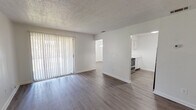 Located at 2301 Old Bainbridge Rd in Tallahassee, Florida, this single-story unit offers a clean, functional layout with a neutral color palette throughout. The open living area features wood-look laminate flooring and a sliding glass door fitted with vertical blinds, allowing generous natural light to filter into the space. The textured popcorn ceiling adds a classic residential character consistent throughout the main living areas.

The galley-style kitchen is efficiently designed with white cabinetry lining both walls, offering ample storage and counter space. Stainless steel appliances — including a range, dishwasher, and refrigerator — complete the kitchen and provide a modern contrast to the white finishes. The kitchen opens conveniently toward the main living space, enhancing the sense of connectivity.

The bedroom is carpeted for comfort and is equipped with a ceiling fan and light fixture, along with a window dressed with blinds that brings in natural light. The bathroom features a full tub and shower combination with a clean white surround, complemented by wood-look flooring that ties into the rest of the unit.

Overall, the space presents a straightforward, well-maintained interior with consistent finishes, making it a practical and accessible living option in Tallahassee.
