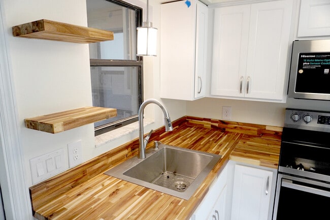 Charming sink nook with wood shelves and outdoor views for simple Yankeetown moments. - 33 63rd St