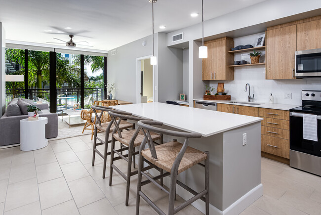 Cocina de concepto abierto con encimeras de cuarzo, isla, electrodomésticos de acero inoxidable y placa para salpicaduras de azulejos - Avalon Doral