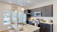 This thoughtfully designed 2-bedroom, 2-bathroom residence offers a cohesive open-concept layout on a single floor, blending modern aesthetics with everyday functionality. The kitchen serves as the heart of the home, showcasing dark espresso cabinetry, granite countertops, stainless steel appliances, and a large central island with bar seating and pendant lighting overhead. Natural light filters in through large windows, brightening the space. Light hardwood-style flooring extends through the main living areas, seamlessly connecting the kitchen to the open living room, which features clean white walls and ample room for comfortable furnishings.

The primary bedroom is generously sized, offering a tranquil retreat with soft carpeting and a dedicated closet. The second bedroom is equally well-lit, benefiting from dual windows that invite natural light and a bright, airy atmosphere. Both bedrooms are served by two full bathrooms. The primary bathroom features a dual-sink vanity with granite countertops, dark cabinetry, and a tub-shower combination. The second bathroom mirrors the same quality finishes with wood-look tile flooring and a tub-shower unit. Two closets provide ample storage throughout the residence, completing this polished and practical home.