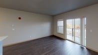 Located at 3410 Orlando St in Port Orchard, Washington, this single-floor unit offers a thoughtfully designed open-concept layout that seamlessly connects the living and kitchen areas. The living space features rich, dark hardwood-style flooring, neutral wall tones, and a sliding glass door that opens to a private balcony with outdoor views — allowing natural light to fill the room.

The kitchen is outfitted with modern dark wood cabinetry, stainless steel appliances including a range, over-the-range microwave, and refrigerator, complemented by clean white countertops and a peninsula with an integrated sink. This layout provides both functionality and an inviting aesthetic that flows naturally into the living area.

The bedroom is carpeted for comfort and features a large window that brings in ample natural light, as well as a spacious walk-in closet with built-in shelving and hanging rods, offering generous storage. The neutral color palette and clean finishes throughout the unit lend a contemporary, move-in-ready feel.

Overall, the unit combines modern finishes with a practical floor plan, creating a cohesive and comfortable living environment well-suited for everyday living in Port Orchard, WA.