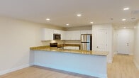 This well-appointed two-story townhome in Columbia, SC offers four bedrooms and two bathrooms across two generously sized floors. The main level features an open-concept kitchen and living area bathed in natural light. The kitchen is outfitted with crisp white shaker cabinetry, granite countertops, a large peninsula island, stainless steel appliances including a refrigerator and microwave, and light wood-style flooring that extends throughout the main living spaces. A dedicated laundry room with wire shelving and washer/dryer hookups adds everyday convenience on this level.

Upstairs, four bedrooms provide ample space, each featuring plush carpeting and ceiling fans. The primary bedroom is generously proportioned and includes direct access to a private en-suite bathroom, as well as a sliding glass door leading to an outdoor balcony with exterior views. Additional bedrooms share access to a full bathroom appointed with a dual-sink granite vanity, white cabinetry, and a tub/shower combination. Two hallways connect the upper-level rooms efficiently, and a dedicated closet provides additional storage. The home's neutral color palette, recessed lighting, and consistent finishes create a clean, cohesive ambiance throughout.