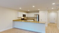 This well-appointed two-story townhome in Columbia, SC offers four bedrooms and two bathrooms across two generously sized floors. The main level features an open-concept kitchen and living area bathed in natural light. The kitchen is outfitted with crisp white shaker cabinetry, granite countertops, a large peninsula island, stainless steel appliances including a refrigerator and microwave, and light wood-style flooring that extends throughout the main living spaces. A dedicated laundry room with wire shelving and washer/dryer hookups adds everyday convenience on this level.

Upstairs, four bedrooms provide ample space, each featuring plush carpeting and ceiling fans. The primary bedroom is generously proportioned and includes direct access to a private en-suite bathroom, as well as a sliding glass door leading to an outdoor balcony with exterior views. Additional bedrooms share access to a full bathroom appointed with a dual-sink granite vanity, white cabinetry, and a tub/shower combination. Two hallways connect the upper-level rooms efficiently, and a dedicated closet provides additional storage. The home's neutral color palette, recessed lighting, and consistent finishes create a clean, cohesive ambiance throughout.