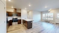 Located in Medical Lake, WA, this well-designed 2-bedroom, 1-bathroom residence offers a thoughtfully laid-out single-floor plan with modern finishes throughout. The open-concept kitchen and living area serves as the heart of the home, anchored by a substantial kitchen island with a white countertop, undermount sink, and ample drawer storage. Rich dark-walnut cabinetry lines the kitchen walls, complemented by a full suite of stainless steel appliances including a range, over-the-range microwave, and refrigerator. Light-toned hardwood-style flooring extends seamlessly through the entire residence, creating a cohesive and clean aesthetic. The living area is bright and open, receiving natural light from a large window with outdoor views of the surrounding neighborhood. Both bedrooms are well-proportioned, each featuring windows that bring in natural light and views of the exterior. The primary bedroom is generously sized and includes access to a dedicated closet with wire shelving for organized storage. A second closet provides additional storage capacity. The bathroom is clean and functional, featuring a tub-shower combination, toilet, and a small high window for natural light. Recessed lighting and neutral wall tones throughout contribute to the residence's modern, move-in-ready appeal.