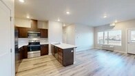 Located in Medical Lake, WA, this well-designed 2-bedroom, 1-bathroom residence offers a thoughtfully laid-out single-floor plan with modern finishes throughout. The open-concept kitchen and living area serves as the heart of the home, anchored by a substantial kitchen island with a white countertop, undermount sink, and ample drawer storage. Rich dark-walnut cabinetry lines the kitchen walls, complemented by a full suite of stainless steel appliances including a range, over-the-range microwave, and refrigerator. Light-toned hardwood-style flooring extends seamlessly through the entire residence, creating a cohesive and clean aesthetic. The living area is bright and open, receiving natural light from a large window with outdoor views of the surrounding neighborhood. Both bedrooms are well-proportioned, each featuring windows that bring in natural light and views of the exterior. The primary bedroom is generously sized and includes access to a dedicated closet with wire shelving for organized storage. A second closet provides additional storage capacity. The bathroom is clean and functional, featuring a tub-shower combination, toilet, and a small high window for natural light. Recessed lighting and neutral wall tones throughout contribute to the residence's modern, move-in-ready appeal.
