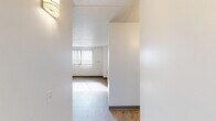 Located at 125 E 156th St in Cleveland, Ohio, this 2-bedroom, 1-bathroom unit offers a practical and well-organized single-floor layout. Throughout the space, light wood laminate flooring and crisp white walls create a clean, bright aesthetic that maximizes the sense of openness.

The living area benefits from natural light streaming through a large window fitted with vertical blinds, casting warm light across the floors. The kitchen, visible in the dollhouse view, features dark cabinetry, a white refrigerator, and a standard range with overhead storage — a functional setup designed for everyday use.

The primary bedroom is generously sized and includes an open closet with a full-width hanging rod, providing ample storage. A second bedroom also features a window with vertical blinds and its own closet with sliding panel doors. Both bedrooms receive natural light and share the same cohesive wood-tone flooring. A third room functions as a compact additional space with a built-in wall heater and window views of the surrounding urban streetscape.

The bathroom is outfitted with a full soaking tub and shower combination, complete with chrome fixtures, a grab bar, and light-toned wall surround panels atop classic tile flooring. The overall design is straightforward and functional, suited for comfortable everyday living in the Cleveland area.
