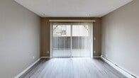 Located at 4922 123rd St SW in Lakewood, Washington, this two-bedroom, one-bathroom unit offers a well-organized single-floor layout. The living room is a welcoming space highlighted by wood-look LVP flooring, neutral gray walls, a textured ceiling, and a full-width sliding glass door fitted with vertical blinds that opens to an outdoor balcony, filling the room with natural light and outdoor views. Baseboard heating runs along the walls for consistent comfort throughout the unit. The kitchen is efficiently designed with white cabinetry, light countertops, and stainless steel appliances, including a range and microwave, all set on light LVP flooring. Both bedrooms feature plush carpeting and neutral tones, with the primary bedroom offering a generous closet. A well-appointed walk-in closet with built-in shelving and hanging rods provides ample storage. The bathroom includes a full tub and shower combination with chrome fixtures. A hallway connects all rooms, and additional closets throughout the unit offer practical storage solutions. The overall aesthetic is clean, neutral, and move-in ready.