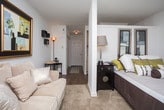 This single-floor residence in Metairie, Louisiana, offers a thoughtfully arranged layout that maximizes comfort and functionality. The living area serves as the heart of the space, featuring plush carpeting, neutral-toned walls, and a window dressed with elegant draping curtains that allow natural light to filter in. Decorative wall art, shadow box shelving, and warm lamp lighting contribute to an inviting, curated ambiance. A structural column subtly defines the transition between seating areas, adding architectural interest.

The kitchen is efficiently designed in a galley-style configuration, outfitted with light wood cabinetry, white appliances including a range and refrigerator, and a stainless steel sink. A skylight overhead brightens the space naturally. Adjacent to the kitchen, a breakfast bar with counter seating provides a convenient dining option.

Wood-look flooring runs through the entryway, kitchen, and transitional areas, while carpet adds warmth to the living space. A hallway with a paneled closet door connects the rooms, enhancing the functional flow of the layout. The bathroom features a vanity with a basin sink, a wall-mounted mirror, overhead cabinetry for additional storage, and a combined tub and shower area, all finished in clean, neutral tones.
