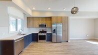 Located at 4077 Glencoe Ave in the desirable Marina del Rey neighborhood of Los Angeles, this modern single-floor unit showcases a clean contemporary design throughout. The open-concept kitchen is a standout feature, outfitted with two-tone cabinetry — warm wood uppers paired with navy lower cabinets — complemented by crisp white quartz countertops, a white subway tile backsplash, and a full suite of stainless steel appliances including a gas range, built-in microwave, side-by-side refrigerator, and dishwasher. Light wood-tone flooring flows throughout the main living areas, adding warmth to the neutral palette. The living room offers a cozy fireplace framed in wood and black surround, with a stylish globe pendant light adding a modern accent. Bedrooms are well-proportioned, featuring wood-look flooring, ample natural light from multiple windows, ceiling fans, and walk-in closets. The bathrooms are finished with large-format tile flooring, wood-toned vanities with under-mount sinks, backlit mirrors, and a frameless glass walk-in shower. Recessed lighting throughout and a thoughtful layout make this a refined and functional living space.