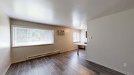 Located at 2890 S Ninth St in Kalamazoo, MI, this one-bedroom, one-bathroom unit offers a practical and well-appointed single-floor layout. The open living and dining area features wood-style flooring, neutral warm-toned walls, and multiple windows that invite generous natural light. A wall-mounted air conditioning unit and baseboard heating ensure year-round comfort. The kitchen is a standout feature, equipped with rich dark-brown shaker-style cabinetry, light countertops, stainless steel appliances including a refrigerator and range, and a built-in dining counter — making efficient use of the available space. The bedroom is carpeted for warmth and comfort, includes a closet with bifold doors, and is illuminated by a window with outdoor views of surrounding greenery. Additional storage is well-addressed throughout the unit, with five closets distributed across the floor plan. The bathroom features a full tub-shower combo with a white surround, a dark-vanity cabinet with a light countertop, and wood-style flooring that complements the rest of the unit. A hallway connects the primary spaces, contributing to a cohesive and functional flow throughout this efficiently designed home.