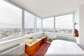 Located in the heart of Jersey City at 36 Journal Square Plaza, this modern two-bedroom, two-bathroom residence offers a thoughtfully designed single-floor layout bathed in natural light. The open-plan kitchen and living area serves as the heart of the home, anchored by expansive floor-to-ceiling windows that frame sweeping panoramic views of the surrounding cityscape and skyline. Light hardwood flooring flows throughout, complementing the clean white walls and contemporary finishes that define the space's modern aesthetic.

The spacious primary bedroom is a standout, featuring a wall of large windows that flood the room with daylight and offer stunning elevated views. It is complemented by generous closet space and a well-appointed en-suite bathroom with a modern vanity, large mirror, and light wood cabinetry. The second bedroom is equally bright and comfortable, with its own access to natural light and ample closet storage.

Both bathrooms are finished with clean-lined fixtures, neutral tile flooring, and streamlined vanities. Additional features include an in-unit laundry room, four closets for abundant storage, and a welcoming hallway entry. The overall ambiance is calm, contemporary, and airy—ideal for those seeking stylish urban living with commanding views.