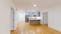 Located at 1435 51st Street in North Bergen, NJ, this well-appointed 3-bedroom, 2-bathroom unit offers a thoughtfully designed single-floor layout. The open-concept living and kitchen area serves as the heart of the home, showcasing light hardwood floors, recessed lighting, and a modern kitchen equipped with gray shaker cabinetry, a white subway tile backsplash, a peninsula with pendant lighting, and stainless steel appliances including a French door refrigerator and built-in microwave. Two hallways connect the living areas to the private quarters, maintaining a clean and organized flow throughout. Each of the three bedrooms features warm hardwood flooring, crisp white walls, and large windows that frame lush, green treetop views, filling the rooms with natural light. The spacious primary bedroom includes a dedicated closet area. The two bathrooms are finished with contemporary gray vanities, white quartz countertops, and large-format tile work. One bathroom offers a full soaking tub with a tiled surround, while the second provides a bright, airy atmosphere with natural light from a window. The unit's clean, modern aesthetic and nature-facing views create a calm and inviting living environment.