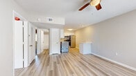 This single-story 2-bedroom, 1-bathroom residence offers a thoughtfully designed layout that maximizes comfort and functionality. The open-concept living and kitchen area serves as the heart of the home, featuring light hardwood-style flooring, neutral toned walls, and a ceiling fan with integrated lighting. Natural light filters in through slatted blinds, creating a bright and welcoming atmosphere. A peninsula counter separates the living space from the kitchen, which is outfitted with white shaker-style cabinetry, stainless steel appliances including a refrigerator, range, and microwave, as well as an in-unit washer and dryer. Both bedrooms are generously proportioned, with the spacious primary bedroom offering a closet and ceiling fan. The second bedroom features sliding glass doors that allow for additional natural light. Both bedrooms are finished with plush carpeting for added comfort. The full bathroom is clean and functional, featuring a white vanity with single sink, a full tub-shower combination, and hardwood-style flooring. Throughout the residence, louvered closet doors and consistent neutral finishes contribute to a cohesive, practical living environment.