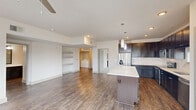 Located at 1851 Knightsbridge Rd in Farmers Branch, TX, this 2-bedroom, 1-bathroom residence offers a thoughtfully designed single-floor layout. The open-concept living and kitchen area forms the heart of the home, featuring rich wood-look flooring that flows throughout the main living spaces. The kitchen is well-equipped with dark espresso cabinetry, white quartz countertops, a subway tile backsplash, stainless steel appliances including a refrigerator, range, and microwave, and a central island with pendant lighting above. Built-in shelving in the living area adds functional display space.

The spacious primary bedroom is filled with natural light from multiple windows and includes a ceiling fan, hardwood-style flooring, and direct access to a walk-in closet. The bathroom features dark cabinetry with a long vanity and wood-look flooring. The second bedroom offers plush carpeting and ample natural light. A dedicated in-unit laundry closet with full-size washer and dryer hookups adds everyday convenience. A separate entryway with an exterior door provides a welcoming transition into the home. Neutral tones and clean finishes throughout create a bright, modern ambiance.