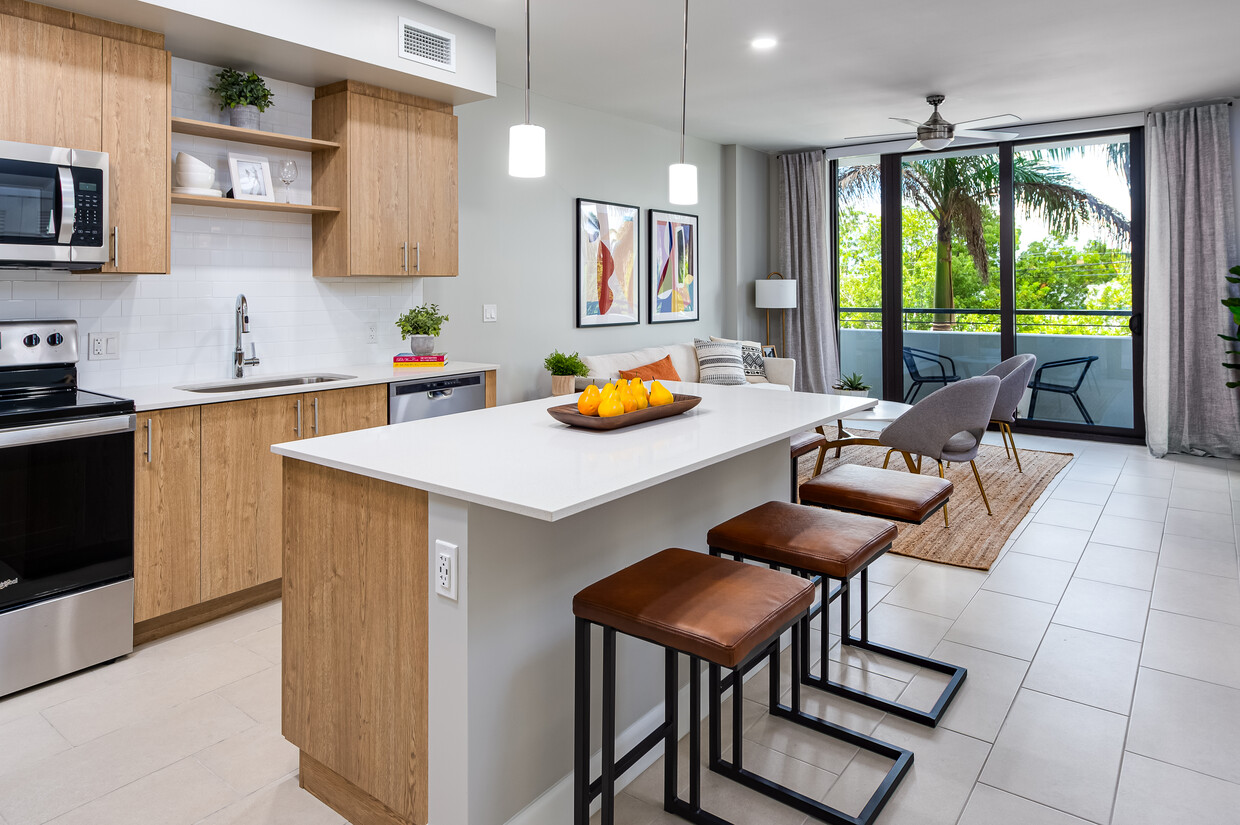 Cocina de concepto abierto con encimeras de cuarzo, isla, electrodomésticos de acero inoxidable y placa para salpicaduras de azulejos - Avalon Doral